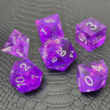 A set of sharp-edge purple resin dice and silver numbering, displayed on a black scale-textured surface.
