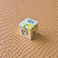 Metal D&D dice set with matte silver finish and painted yellow flowers, displayed on textured leather background.