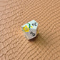 Metal D&D dice set with matte silver finish and painted yellow flowers, displayed on textured leather background.