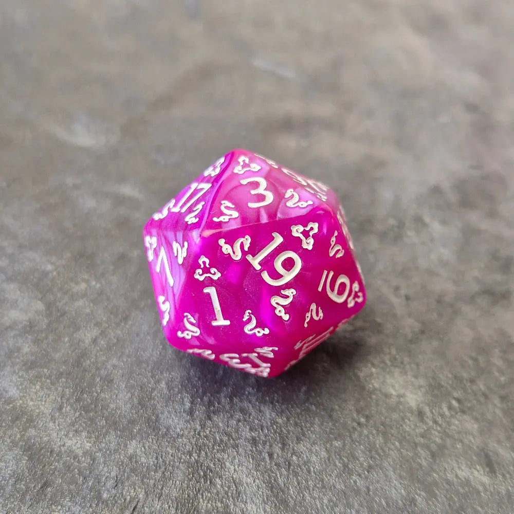 Purple acrylic D20 with white ornate numbering, styled with arcane fantasy motifs, displayed on a stone surface.