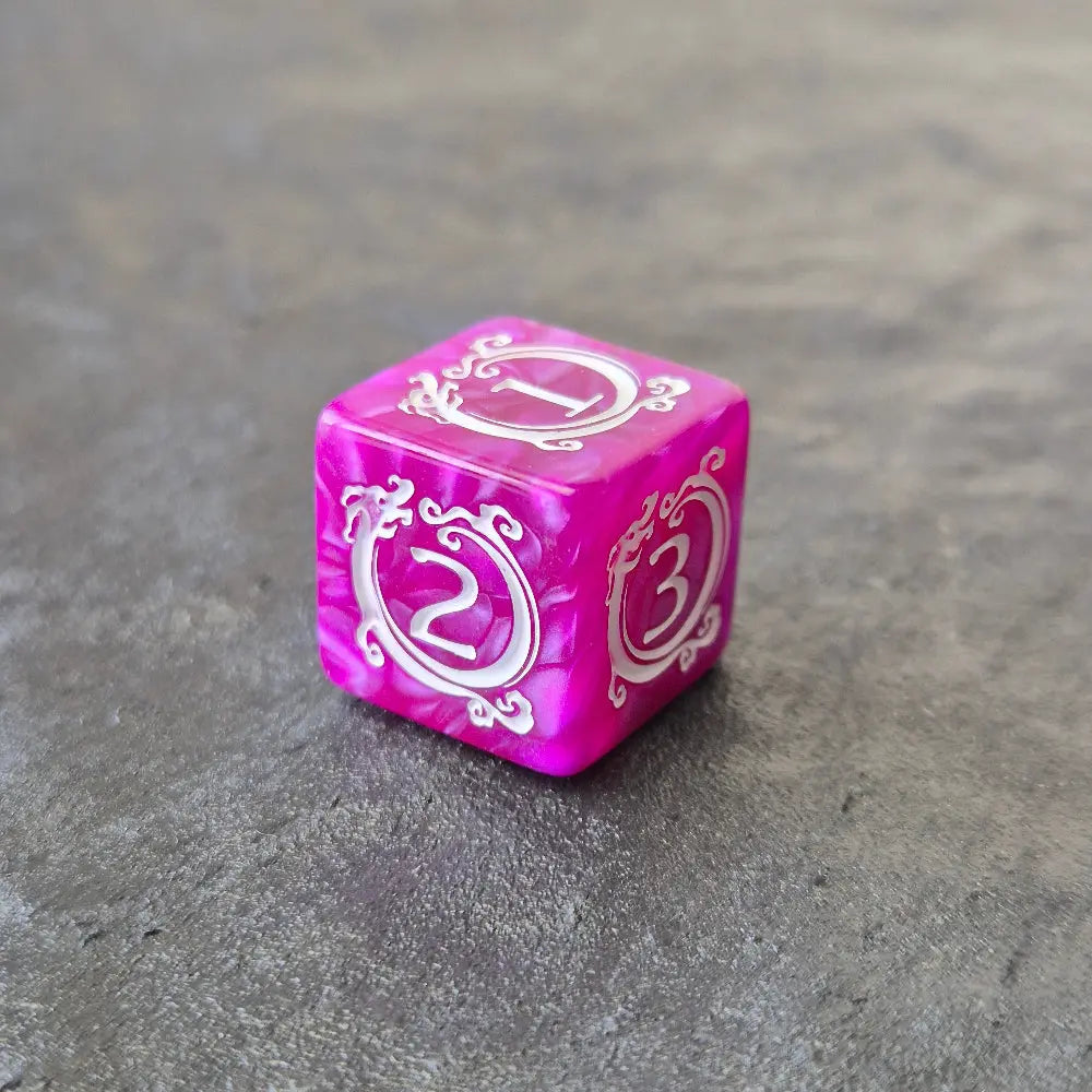 Purple acrylic D6 with white ornate numbering, styled with arcane fantasy motifs, displayed on a stone surface.