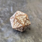 Brown khaki acrylic D20 with white ornate numbers, arranged on a textured grey stone background.
