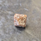 Brown khaki acrylic D10 with white ornate numbers, arranged on a textured grey stone background.