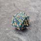 Acrylic D20 with emerald green swirls and antique gold arcane-style numbering, displayed on a textured dark surface.