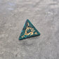 Acrylic D4 with emerald green swirls and antique gold arcane-style numbering, displayed on a textured dark surface.
