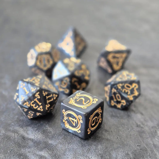 Acrylic D&D dice set with swirling black design and ornate golden numbering, displayed on a dark background.