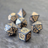 Acrylic D&D dice set with swirling black design and ornate golden numbering, displayed on a dark background.
