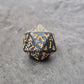 Acrylic D20 dice with swirling black design and ornate golden numbering, displayed on a dark background.