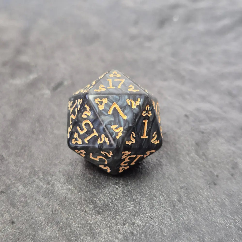 Acrylic D20 dice with swirling black design and ornate golden numbering, displayed on a dark background.