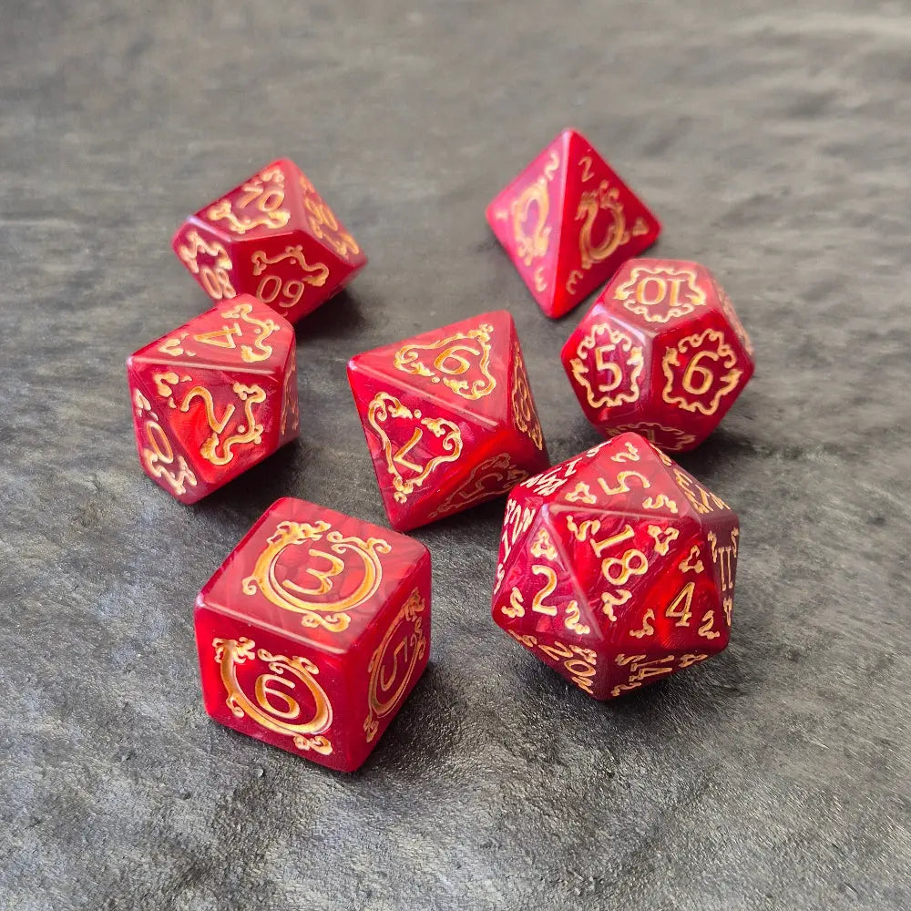 Red acrylic D&D dice set with golden arcane-style numbers and swirling patterns, displayed on a textured grey background.