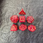 Red acrylic D&D dice set with golden arcane-style numbers and swirling patterns, displayed on a textured grey background.
