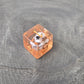 D6 Orange resin polyhedral dice with embedded cow miniatures and gold numbering, displayed on a textured grey background.