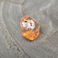 D10 Orange resin polyhedral dice with embedded cow miniatures and gold numbering, displayed on a textured grey background.