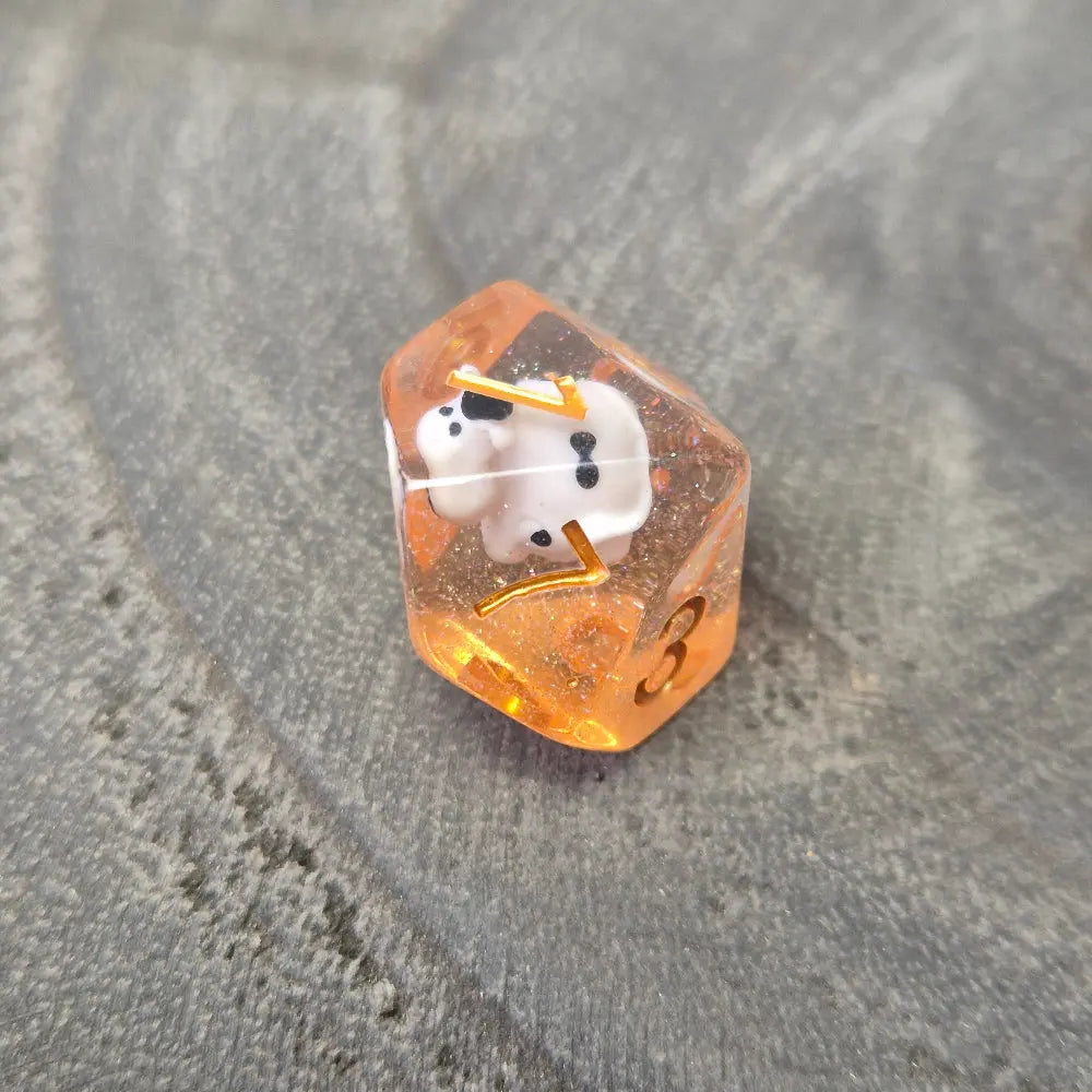 D10 Orange resin polyhedral dice with embedded cow miniatures and gold numbering, displayed on a textured grey background.