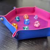 Foldable hexagon-shaped dice trays in pink & purple shown open and filled with colorful polyhedral dice.