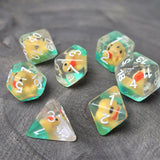 Close-up of transparent resin dice with tiny yellow ducks inside, placed on a textured stone surface.