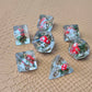 Clear resin D&D dice with red mushroom and moss encased inside, golden numbers, set on a textured leather background.