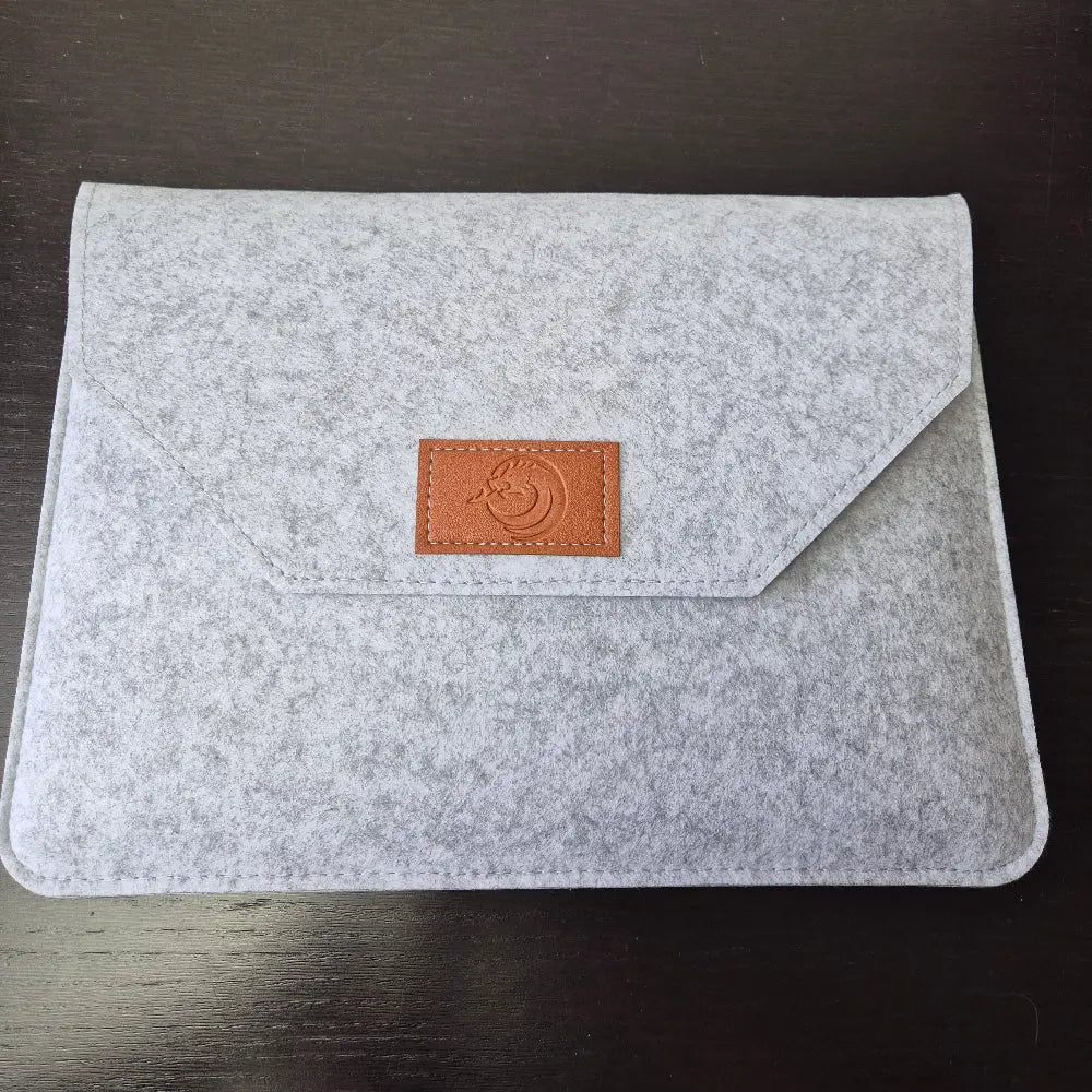 Foldable four-panel Dungeon Master screen with embossed fantasy scenes and included felt sleeve, displayed on a dark tabletop.