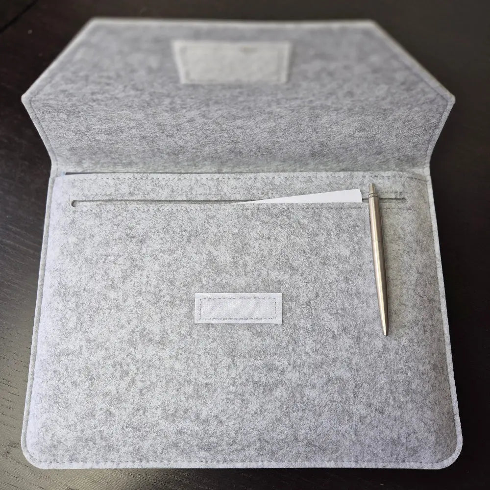 Foldable four-panel Dungeon Master screen with embossed fantasy scenes and included felt sleeve, displayed on a dark tabletop.